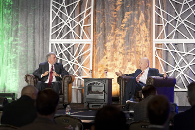 Corporate event photography, executive fireside chat interview on stage at business conference.