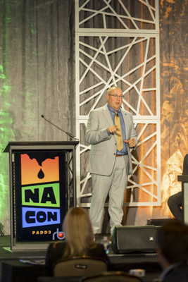 Keynote speaker at NA CON conference, executive presenting on stage at industry event.