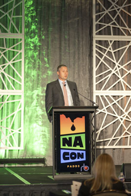 Keynote speaker at NA CON conference, executive presenting on stage at industry event.